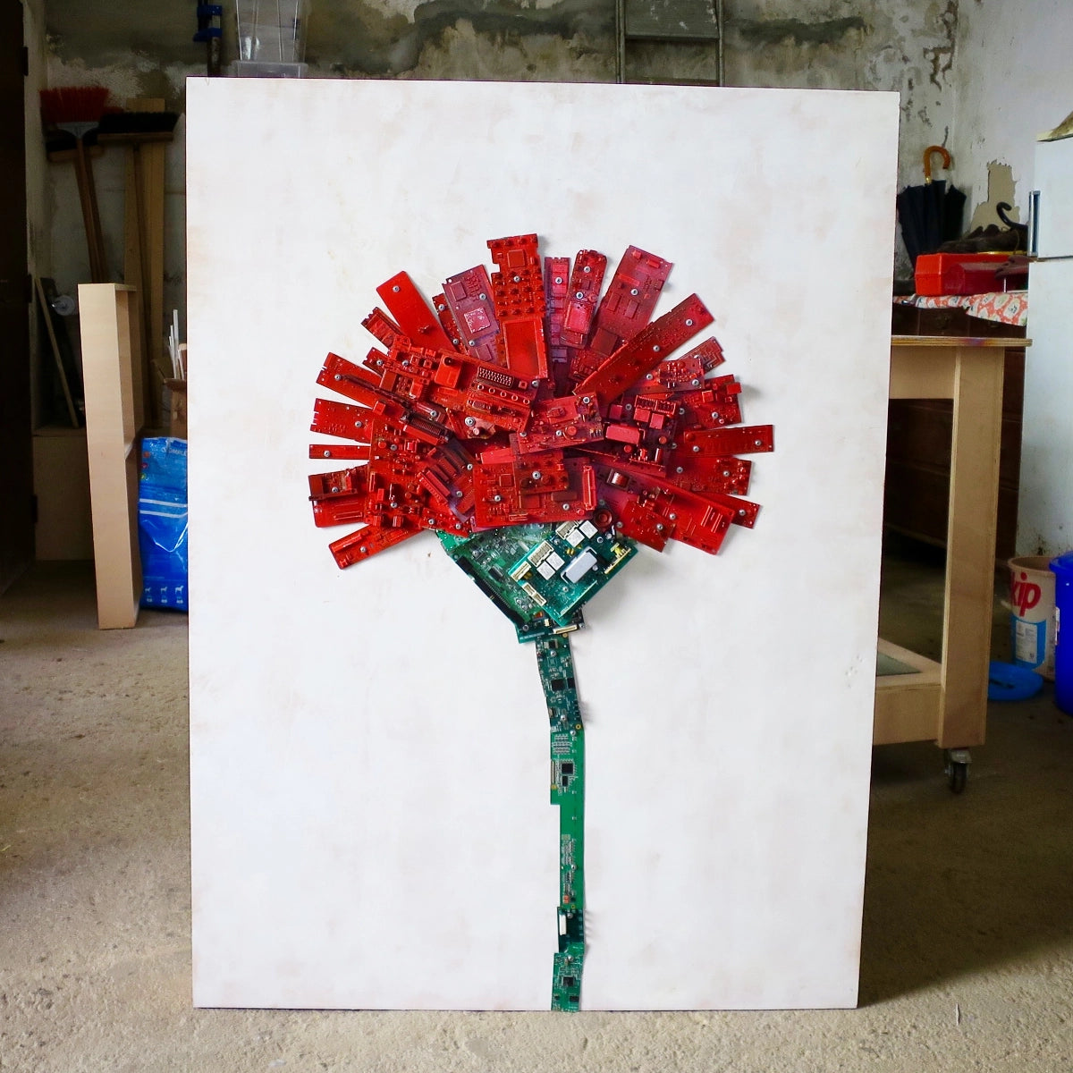 Electronic waste sculpture depicting a red carnation assembled from circuit boards and computer components.